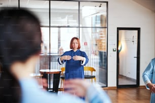 Calm woman putting hands forward while coordinating her movements in qigong class