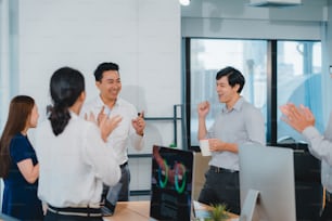 Millennial group of young businesspeople Asia businessman and businesswoman celebrate giving five after dealing feeling happy and signing contract or agreement at meeting room in small modern office.