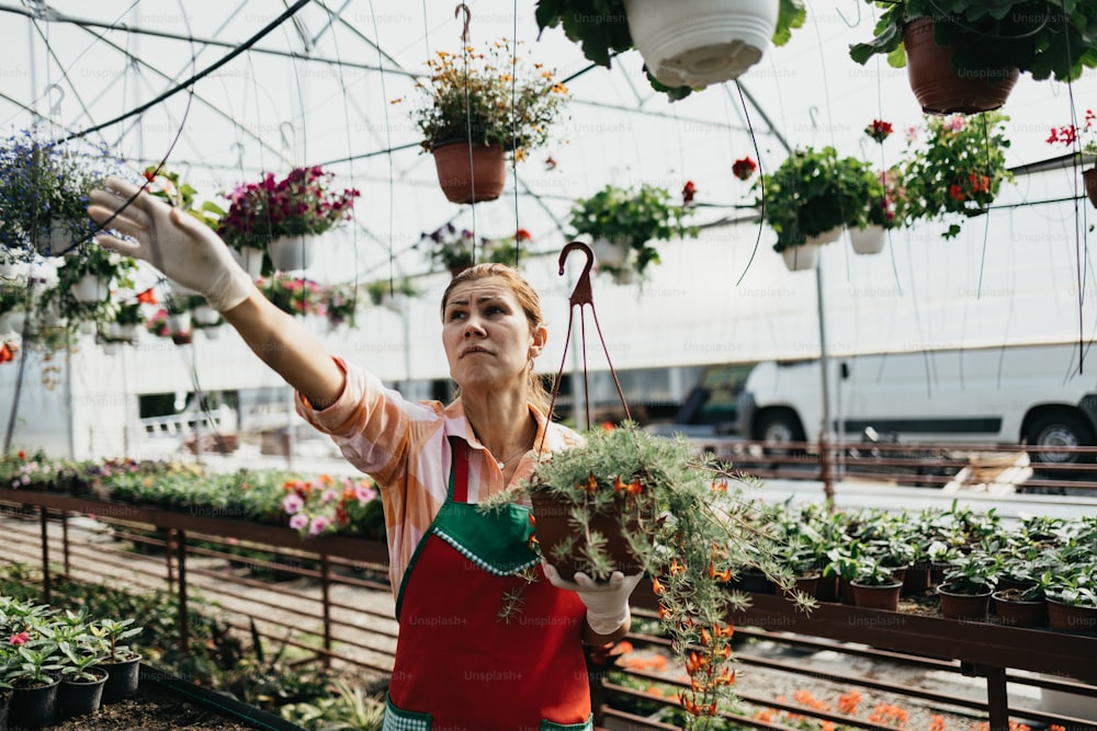 Mujer adulta joven feliz y positiva que trabaja en invernadero y disfruta de hermosas flores.
