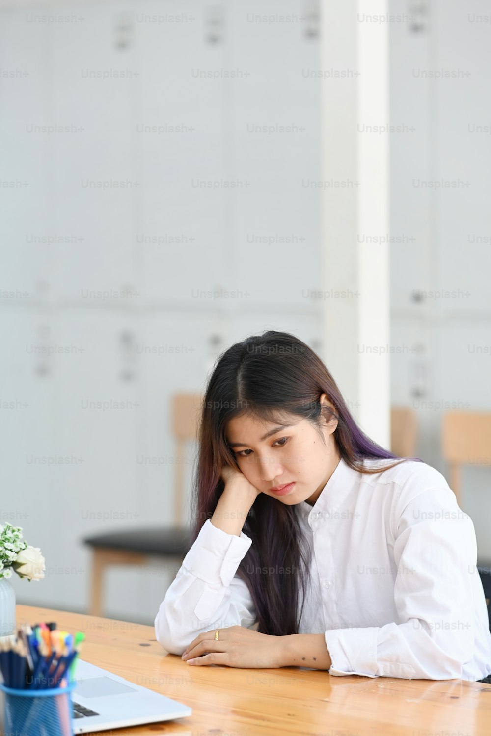 Oficinista joven aburrida sentada en su lugar de trabajo.