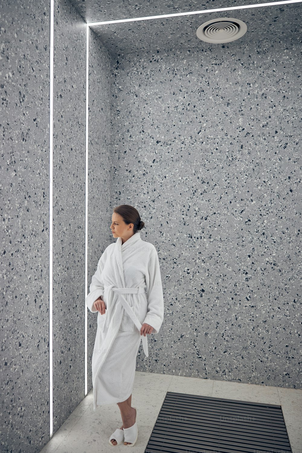 Full-sized portrait of a tranquil lady in a terry bathrobe and slippers staring at the wall