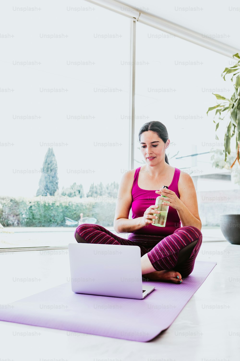 hispanic woman sitting on the floor watching yoga videos on laptop at home in Latin America