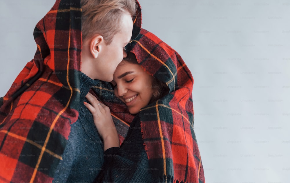 With red towel. Cute young couple embracing each other indoors in the studio.