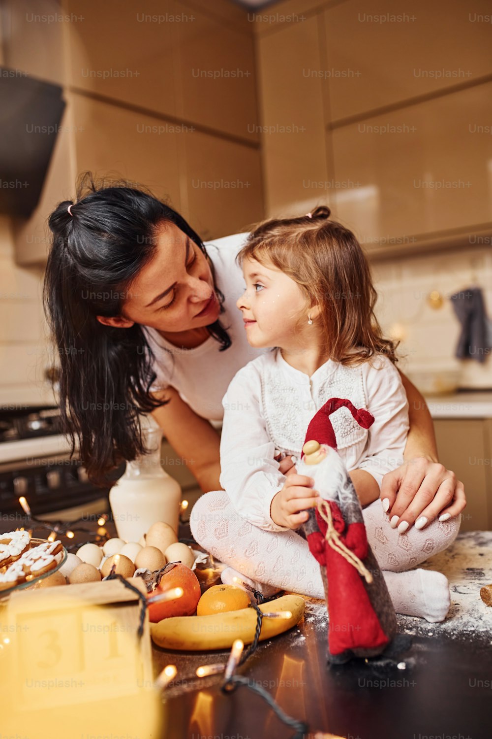 Mother with her little daughter preparing food on kitchen and have fun.