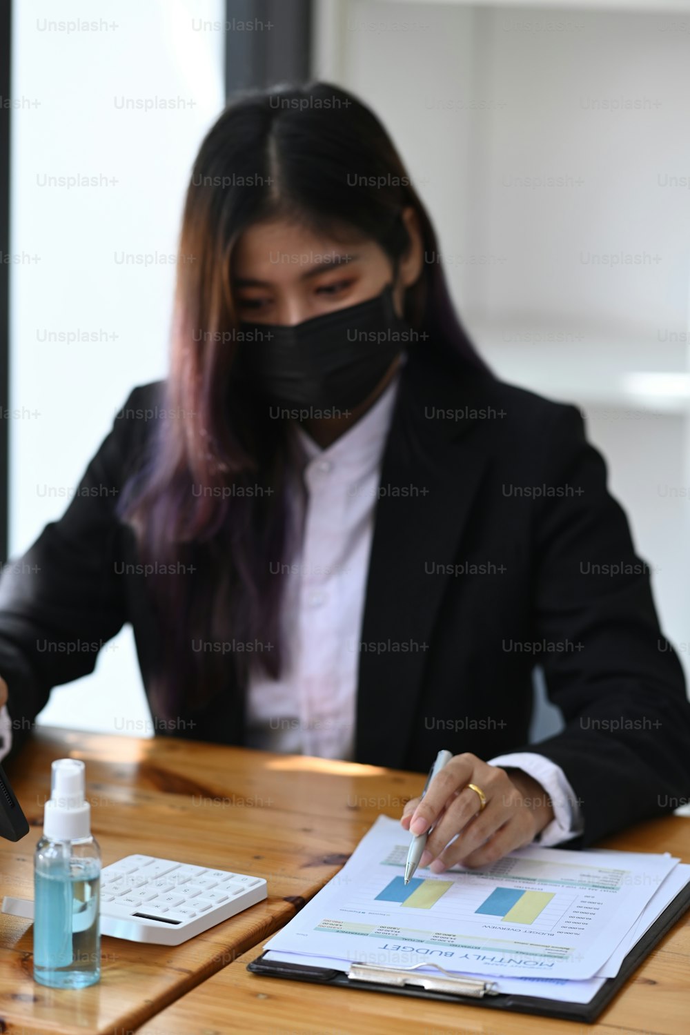 Businesswoman in protective mask analyzing business data at office.