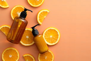 Cosmétiques SPA naturels avec de la vitamine C et des tranches d’orange sur fond de couleur. Pose à plat, vue de dessus.