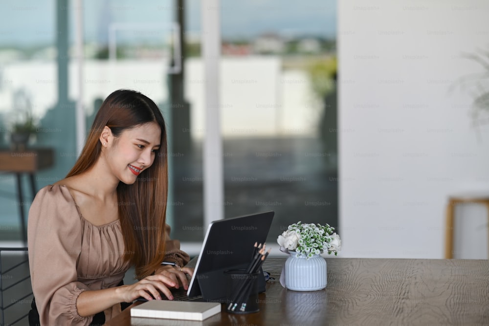 Smiling female working with laptop in office.
