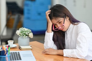 Bored young female sitting at her workplace in the office.