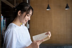 Mujer joven leyendo un libro en la biblioteca.