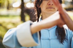 野外で練習する女性武道家とデモンストレーションの手のひらで拳の挨拶