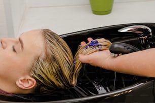Parrucchiere che applica lo shampoo colorante viola dopo la tintura dei capelli.