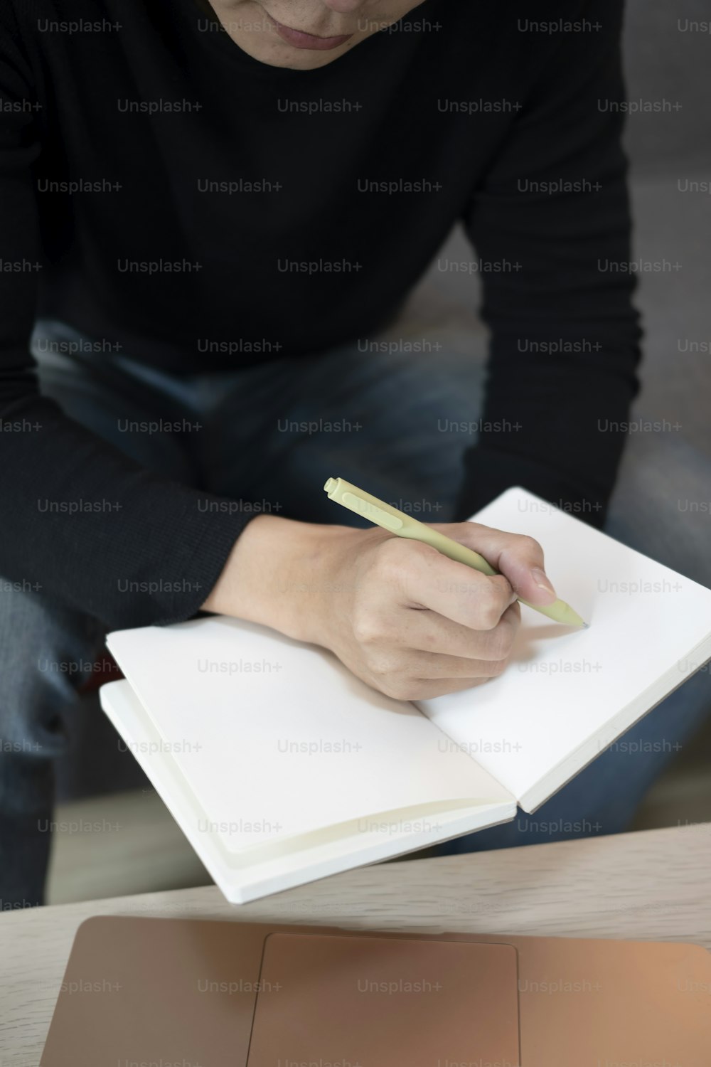 Man sitting on sofa and making note on notebook.