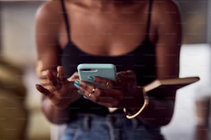 Vista de cerca de las manos de la mujer afroamericana con smarthone.