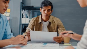 Happy young Asia businessmen and businesswomen meeting brainstorming some new ideas about project to his partner working together planning success strategy enjoy teamwork in small modern home office.