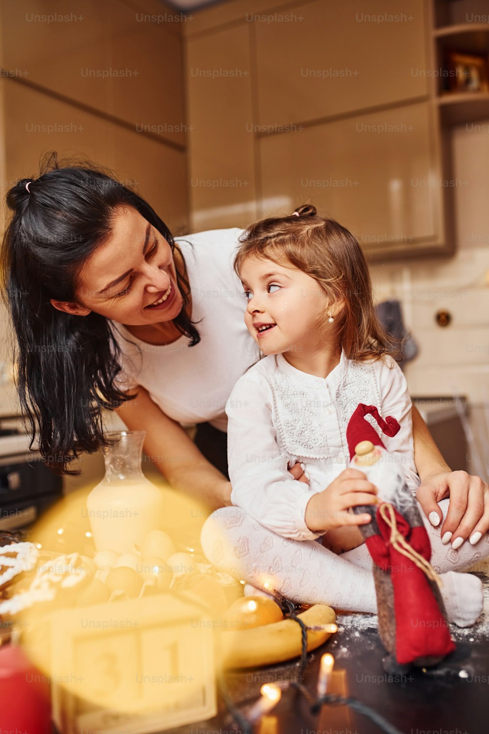 Mother with her little daughter preparing food on kitchen and have fun.