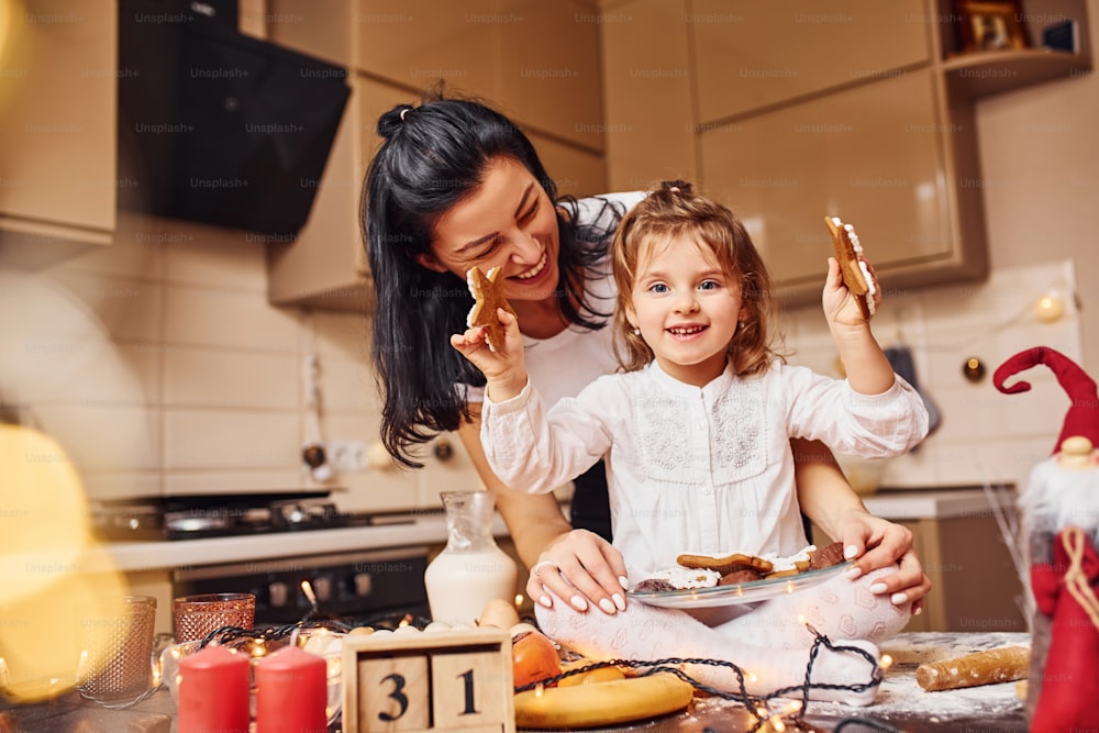 Mãe com sua filhinha preparando comida na cozinha e se divertindo.