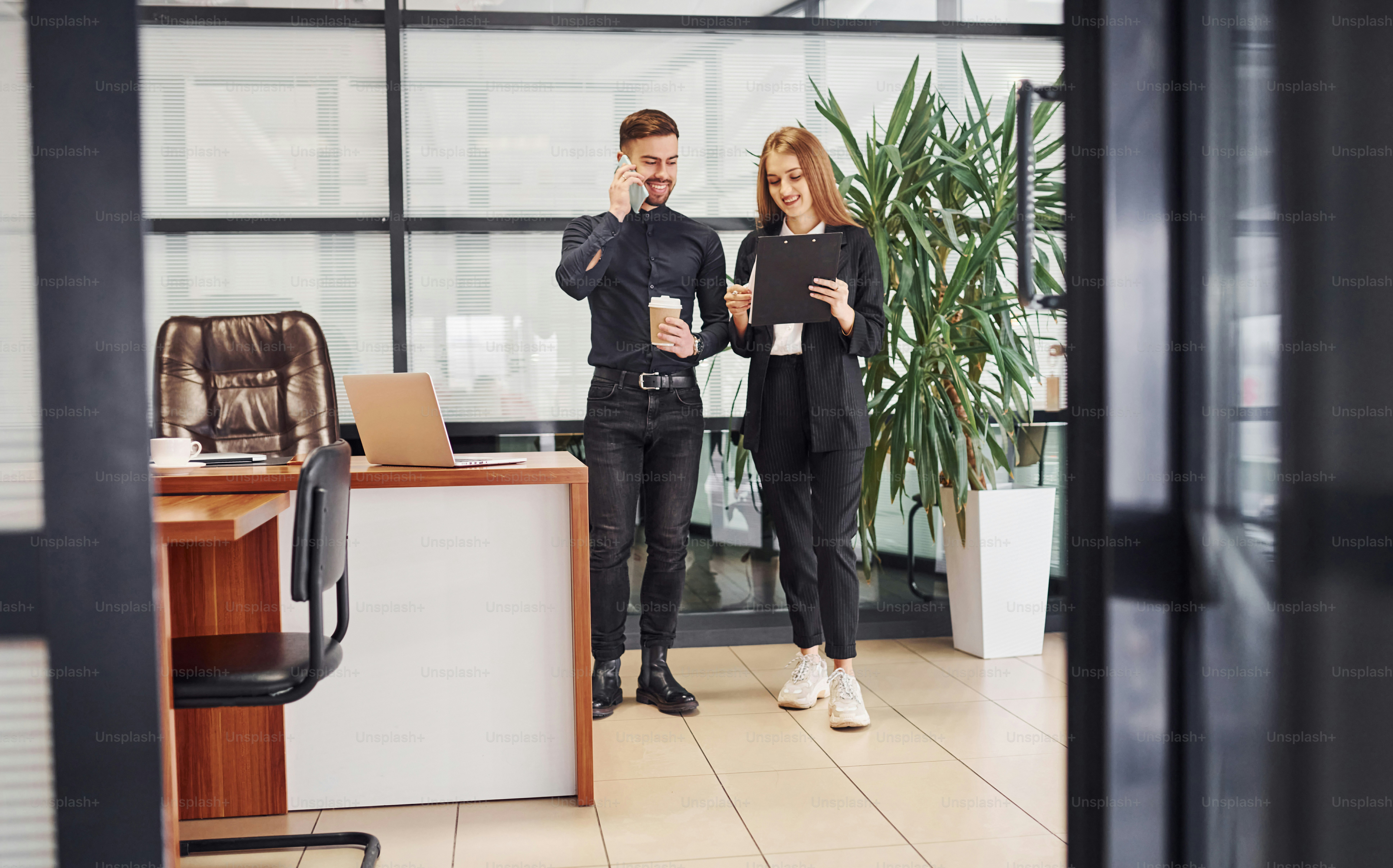 Woman and man in formal clothes with documents talking to each other in the office.