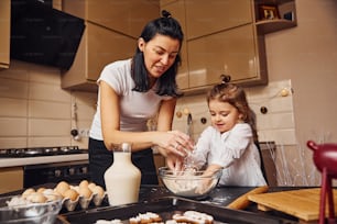Mutter mit ihrer kleinen Tochter bereitet Essen in der Küche zu und hat Spaß.
