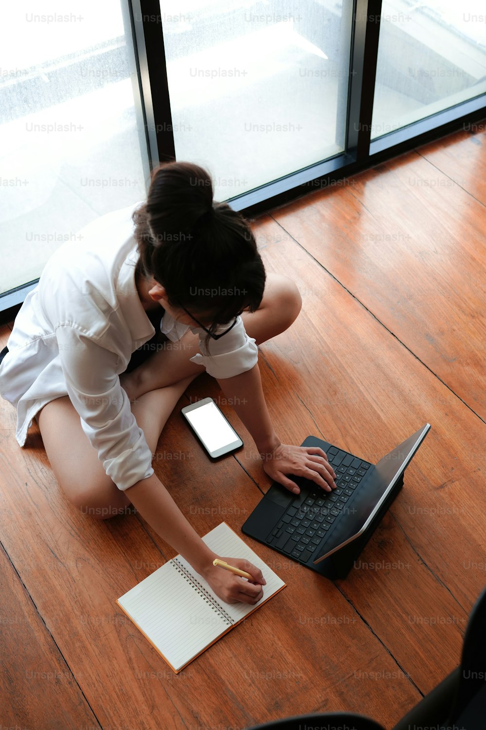 Woman using computer tablet and making note on notebook.