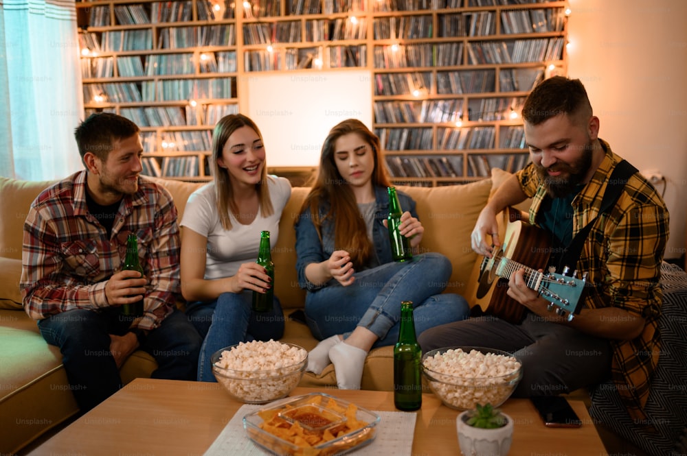 ギターを弾きながらビールを飲みながら、ナチョスやポップコーンを食べながら楽しむホームパーティーの友人たち