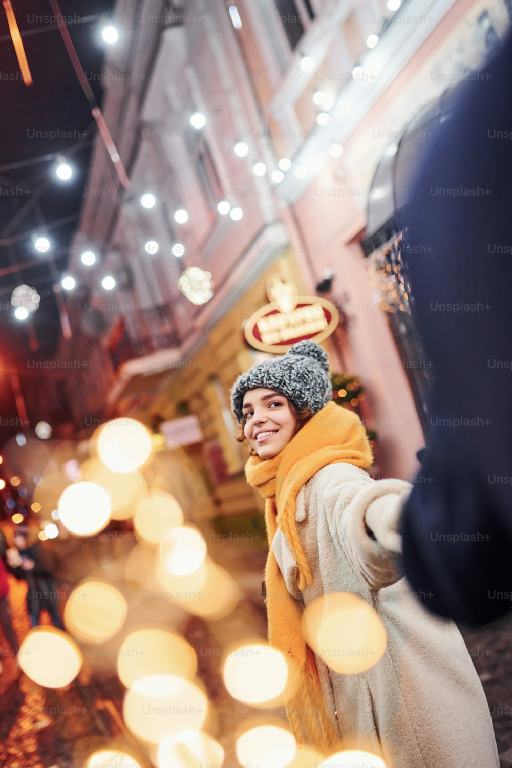 따뜻한 옷을 입은 행복한 젊은 커플이 함께 크리스마스 장식 거리에 있다.
