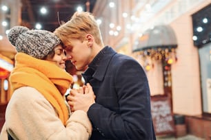 Vicinanza delle persone. La giovane coppia felice in vestiti caldi è sulla strada decorata di Natale insieme.