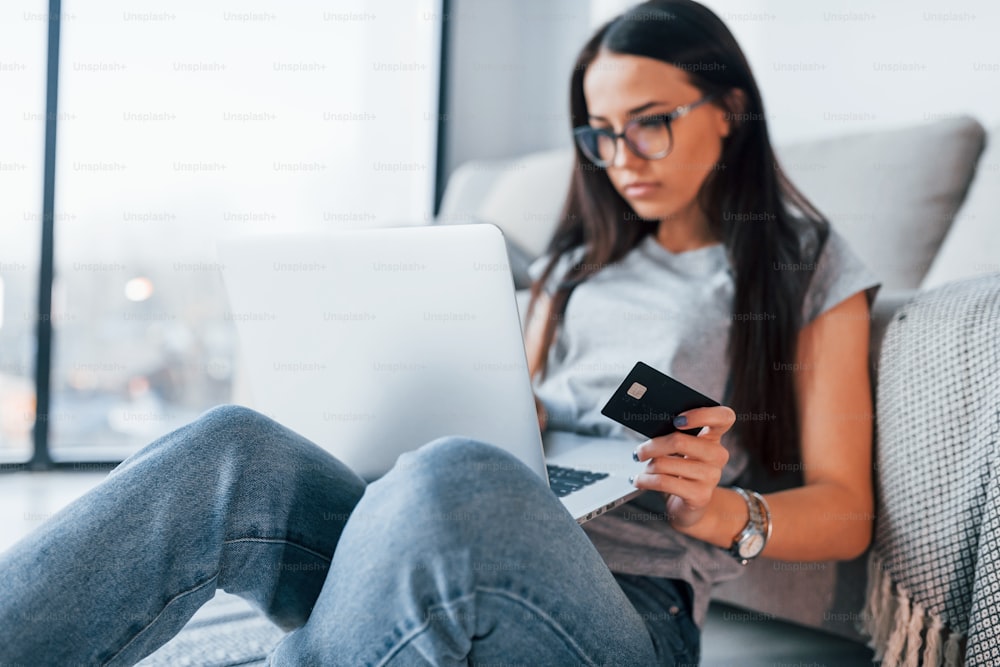 Young beautiful woman in casual clothes sitting at home alone with laptop and credit card.