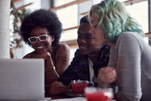 Group of multiracial people that sitting together by table and using laptop.