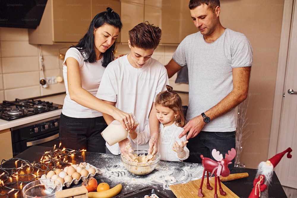 La famiglia felice si diverte in cucina e prepara il cibo.