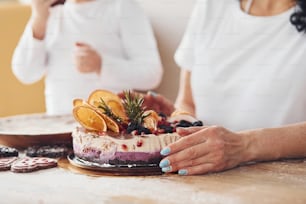 Vue rapprochée d’une femme avec sa petite-fille préparant un gâteau diététique sur la cuisine.