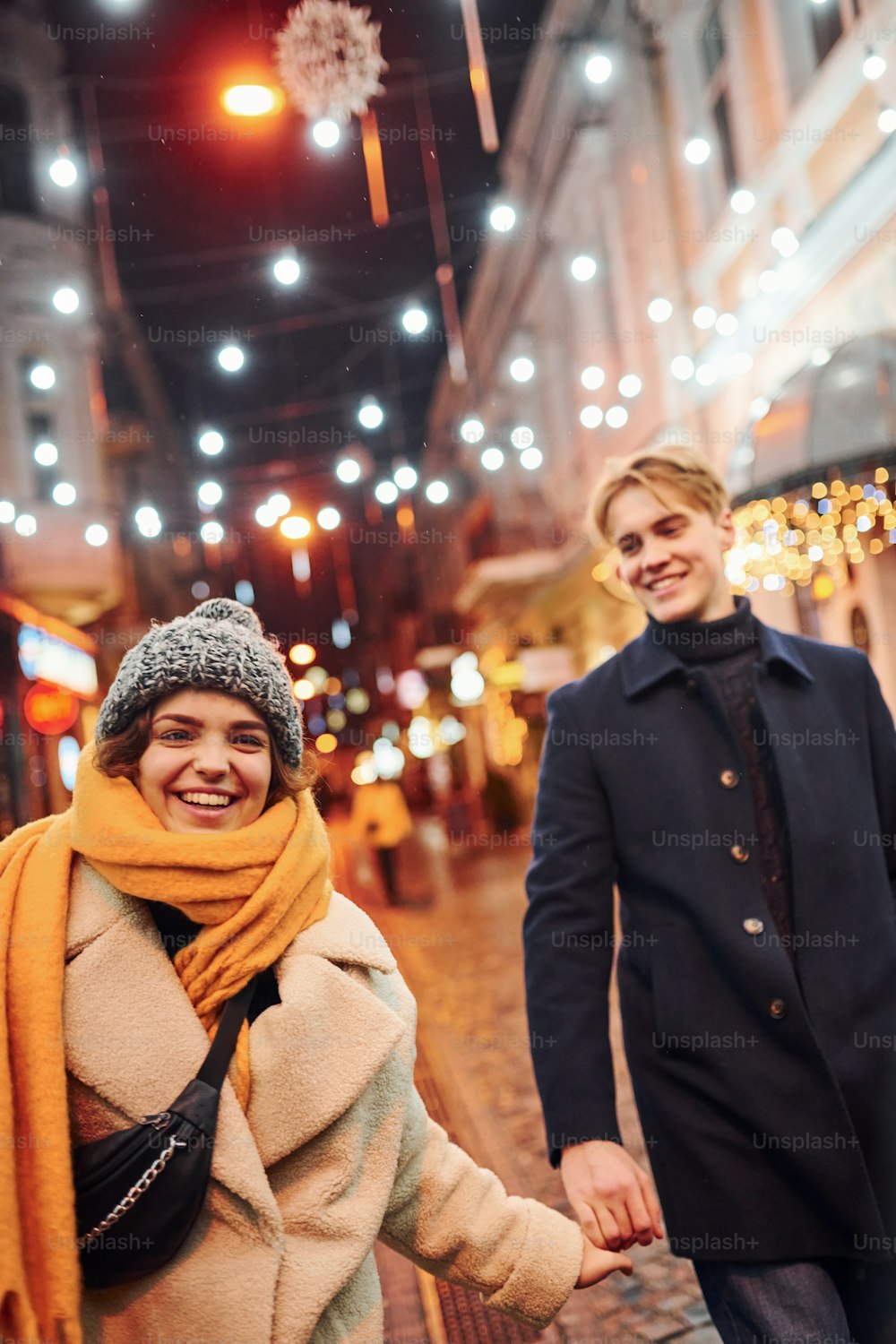 クリスマスデコレーションされた通りを一緒に散歩するカップル。