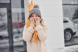 Cheerful young girl smiling standing and smiling outdoors. Snow is falling.