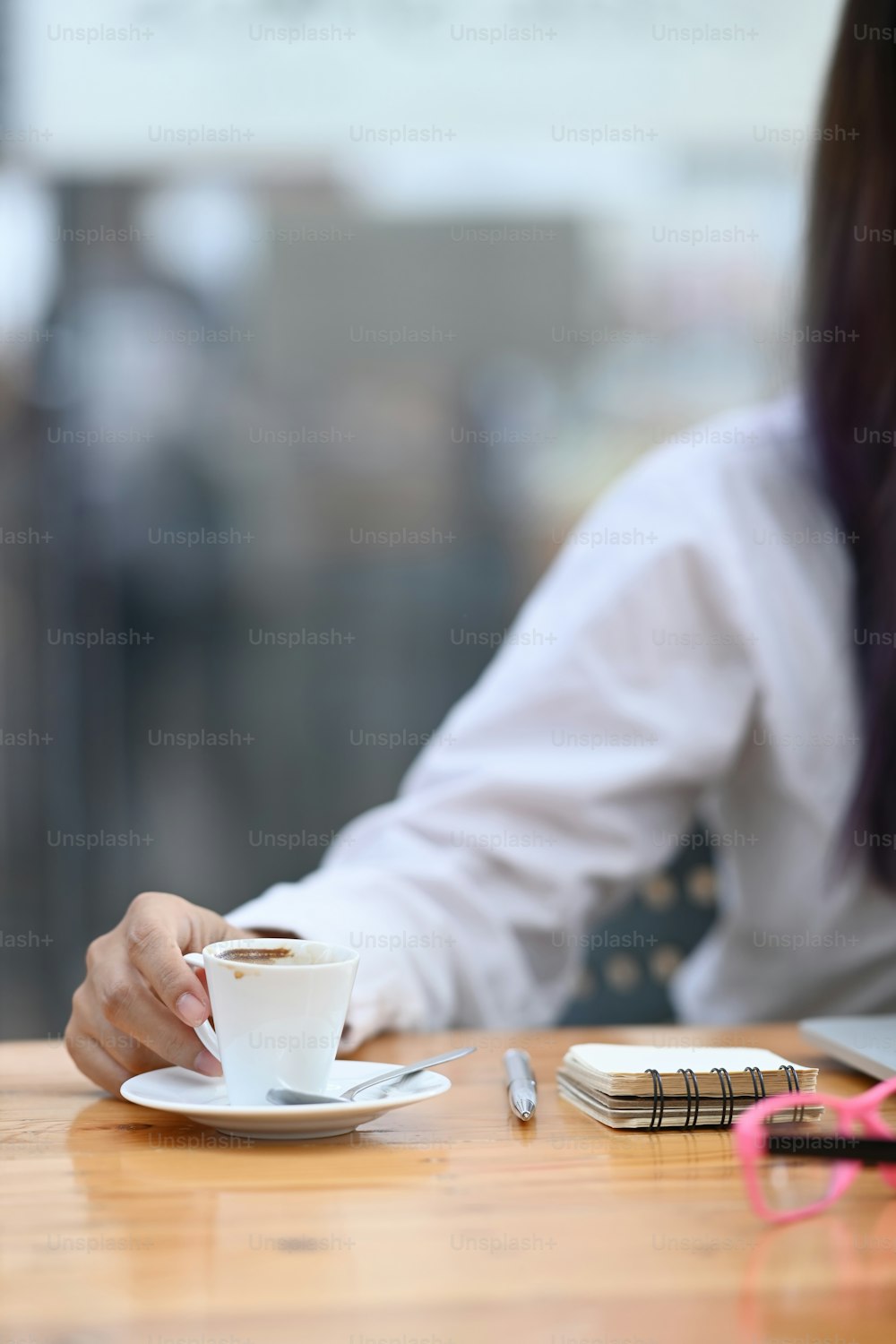 Geschäftsfrau hält eine Tasse Kaffee in der Hand, während sie am Schreibtisch sitzt.