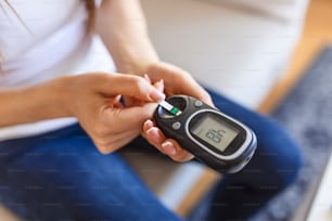 自宅で血糖値をチェックする血糖値計を持つ女性。糖尿病、ヘルスケアのコンセプト