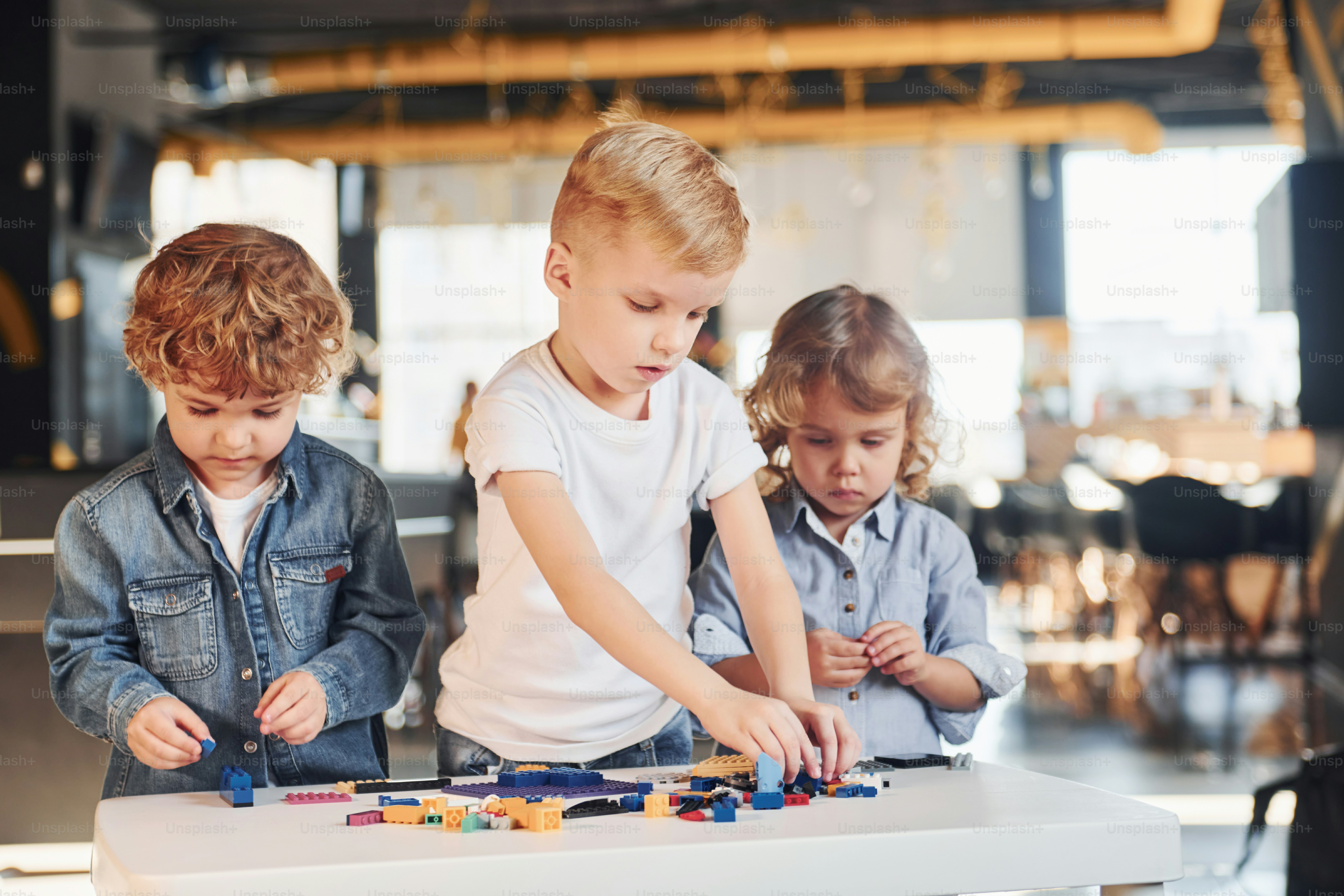 Little friends have fun with construction toys in playroom. Kindergarten educational games.