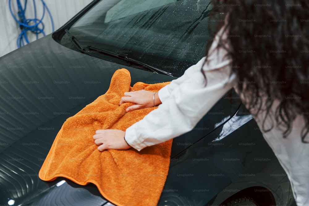 現代の自動車を掃除する機器を持つ女性。サービスの概念。