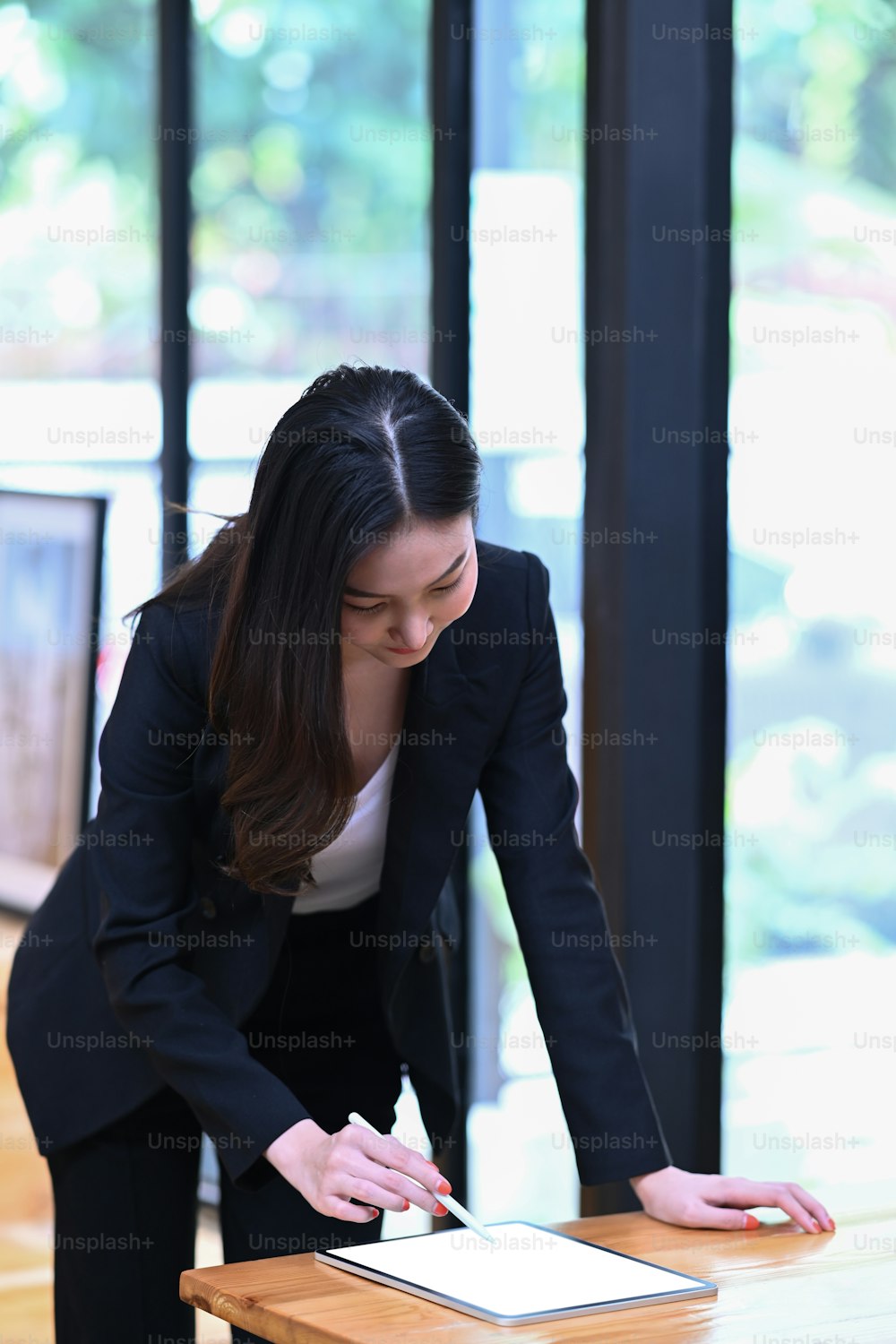 Busy businesswoman standing and working with digital tablet in office room.