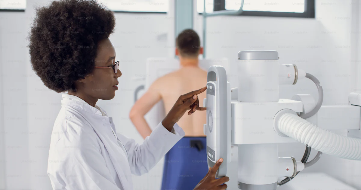 Female Aro American radiologist technician setting up machine to ...