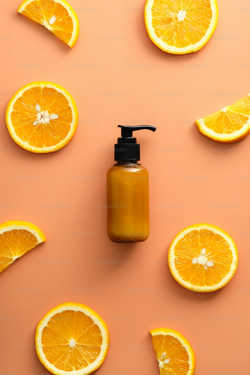 Vitamin C cosmetic lotion pump bottle and orange slices on color background. Citrus beauty product design.