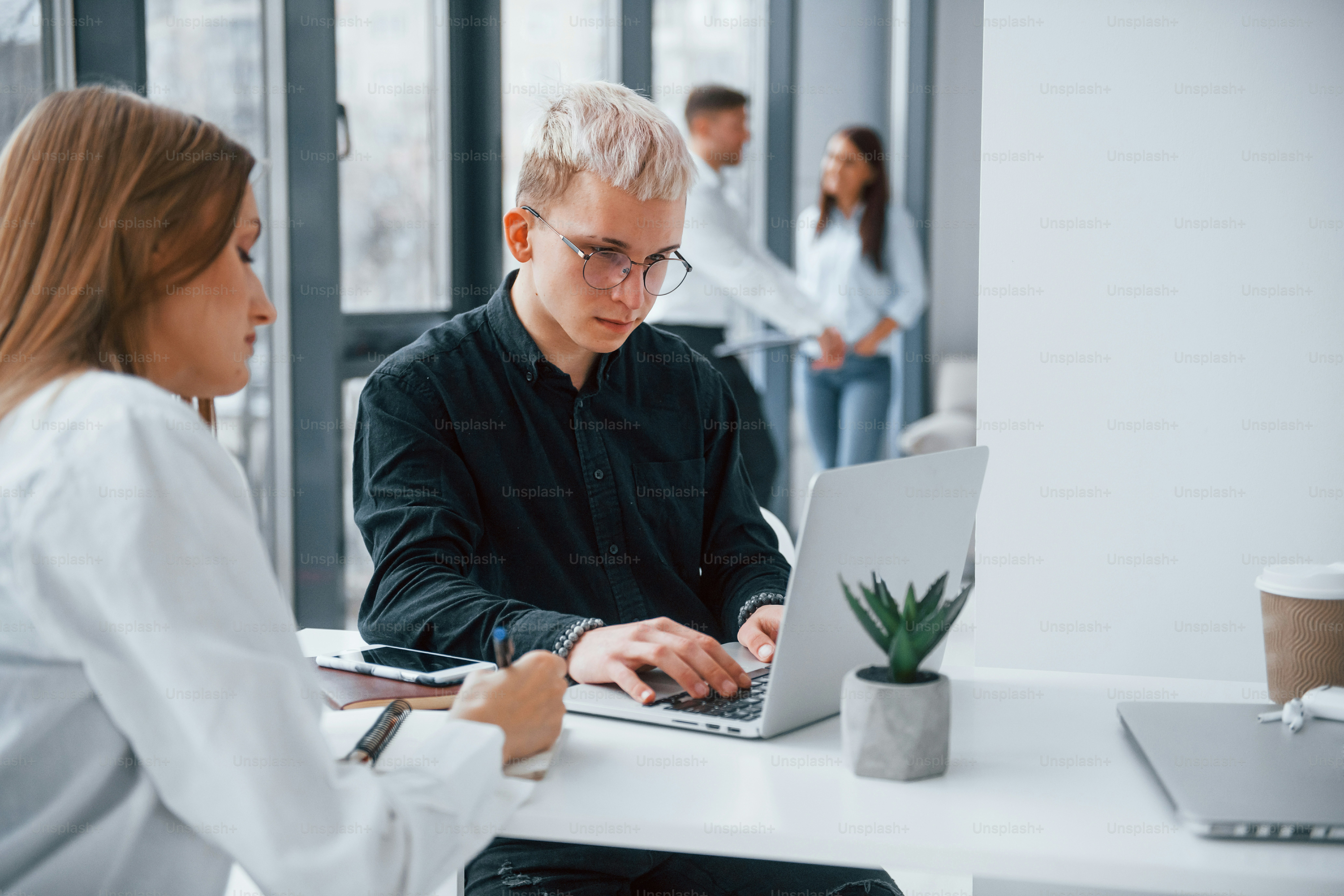 Close up view of woman and man that working and communicating together indoors in office by laptop.