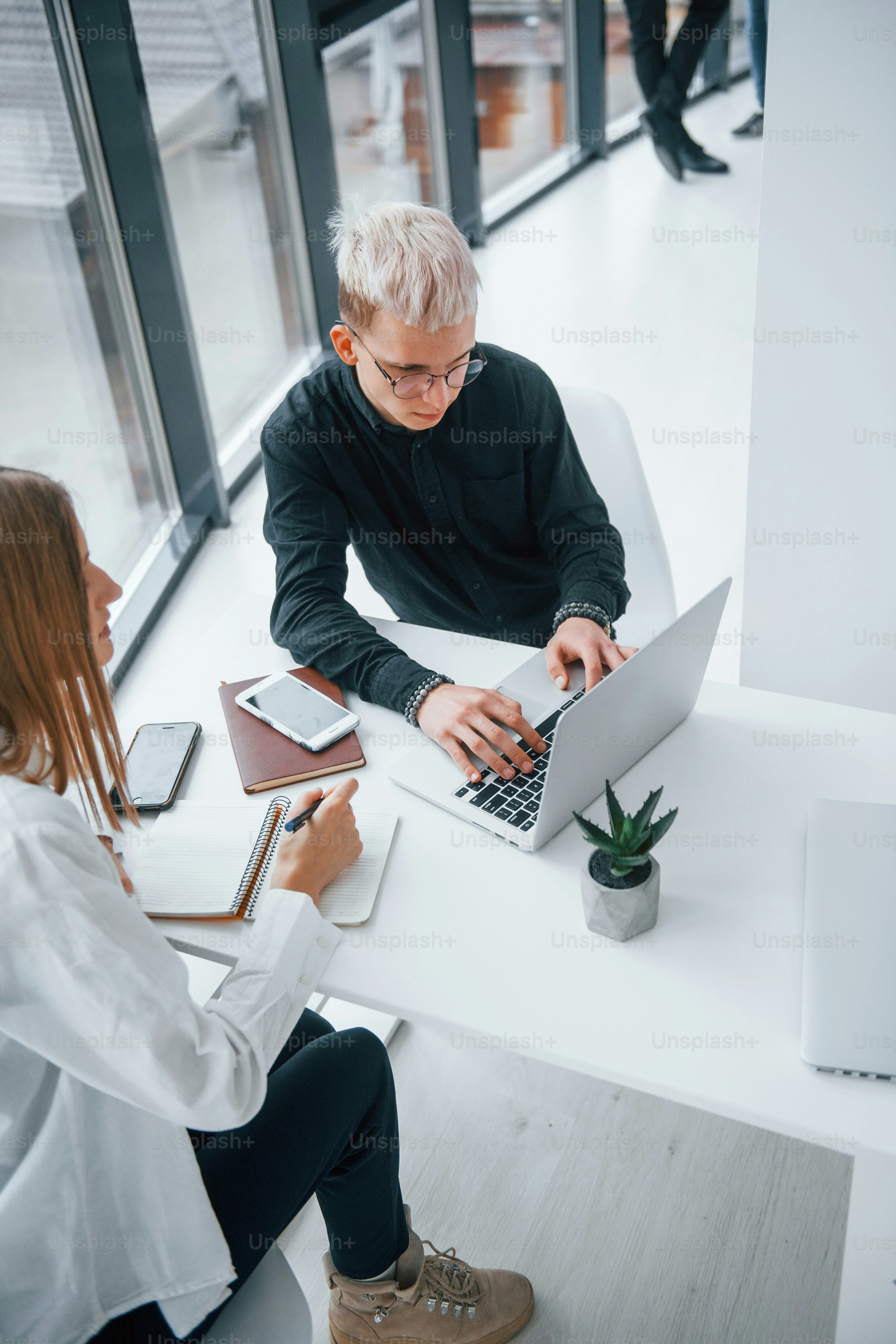 Close up view of woman and man that working and communicating together indoors in office by laptop.