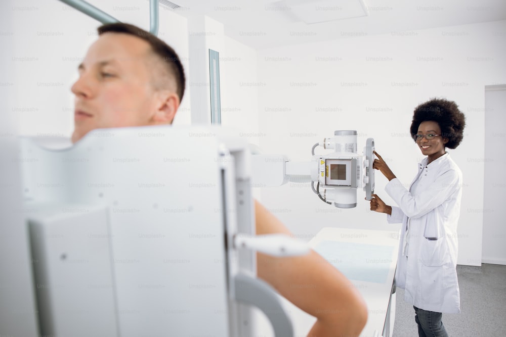 엑스레이 흉부 스캔 중 현대 병원에 서 있는 청년, 여성 아프리카계 미국인 의료 기술자가 엑스레이 기계로 작업합니다. 골절, 흉부, 암 또는 종양 스캔