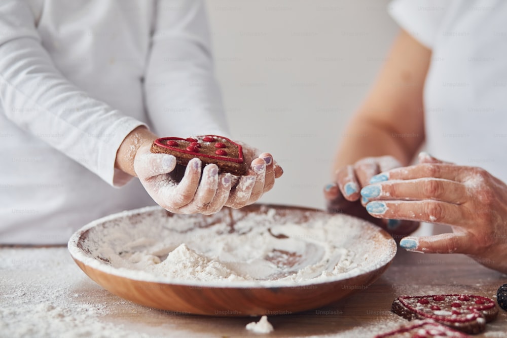 Close up view of woman with her granddaughter preparing food with flour on kitchen.
