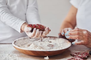 Close up view of woman with her granddaughter preparing food with flour on kitchen.