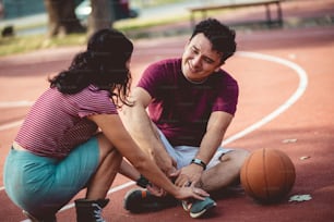 Pareja en la cancha de baloncesto. Hombre que tiene una lesión.