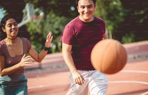 Pareja joven jugando al baloncesto. La atención se centra en la mujer y el hombre.