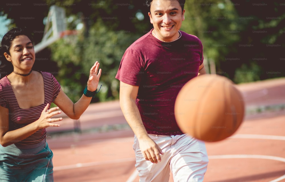 Junges Paar beim Basketballspielen. Im Mittelpunkt stehen Frau und Mann.