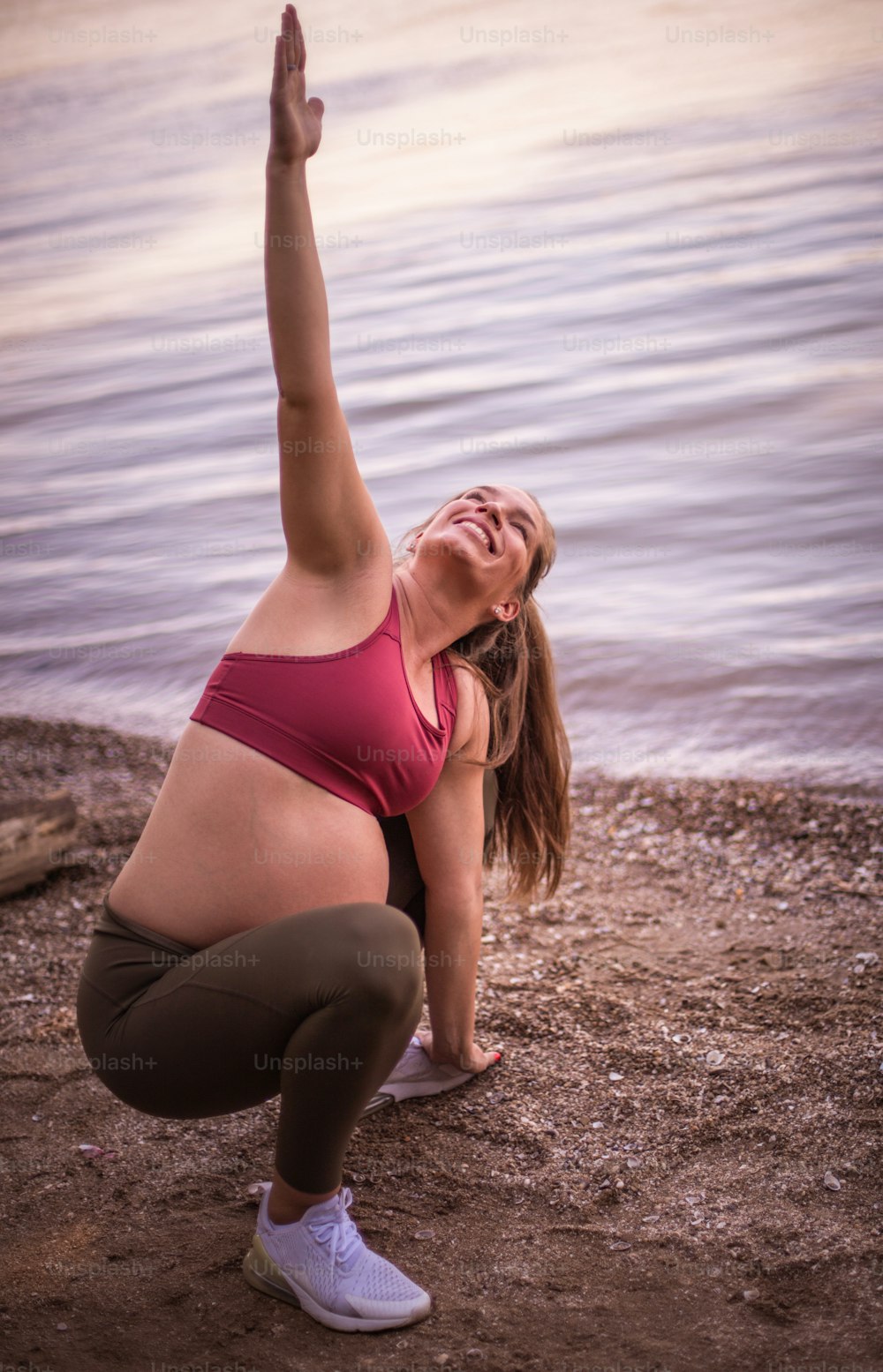 Mulher grávida que trabalha yoga na praia.