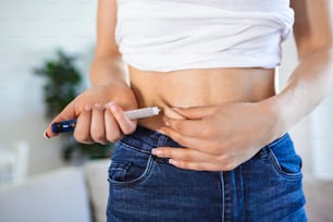 집에서 인슐린 주사를 하기 위해 인슐린 펜을 사용하는 당뇨병 환자. 젊은 여자는 당뇨병을 통제합니다. 당뇨병 생활 방식