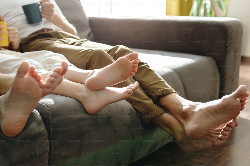 Famiglia a piedi nudi seduta sul divano nel soggiorno